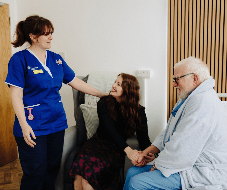 a nurse talking to a patient and family member in a ward room